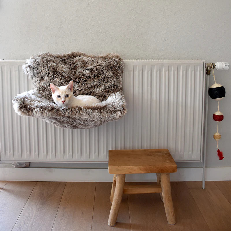 Hamac radiateur beige posé sur un radiateur avec un chat